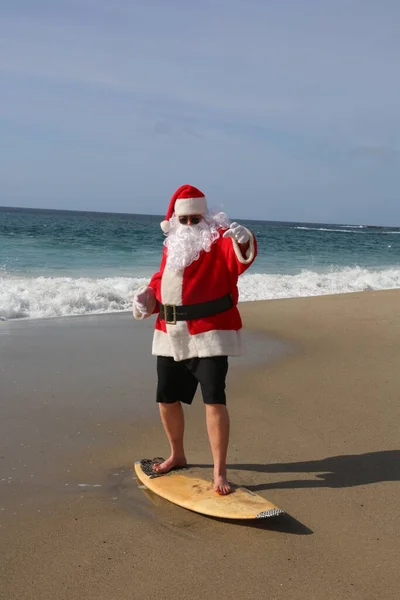 给圣诞老人冲浪 圣诞节 圣诞节假期 冲浪圣诞老人 冲浪板 挂十号圣诞老人在度假时乘风破浪 圣诞前夕前的圣诞老人 圣诞老人和冲浪板 圣诞老人在他的冲浪板上冲浪 浪涌上来 — 图库照片