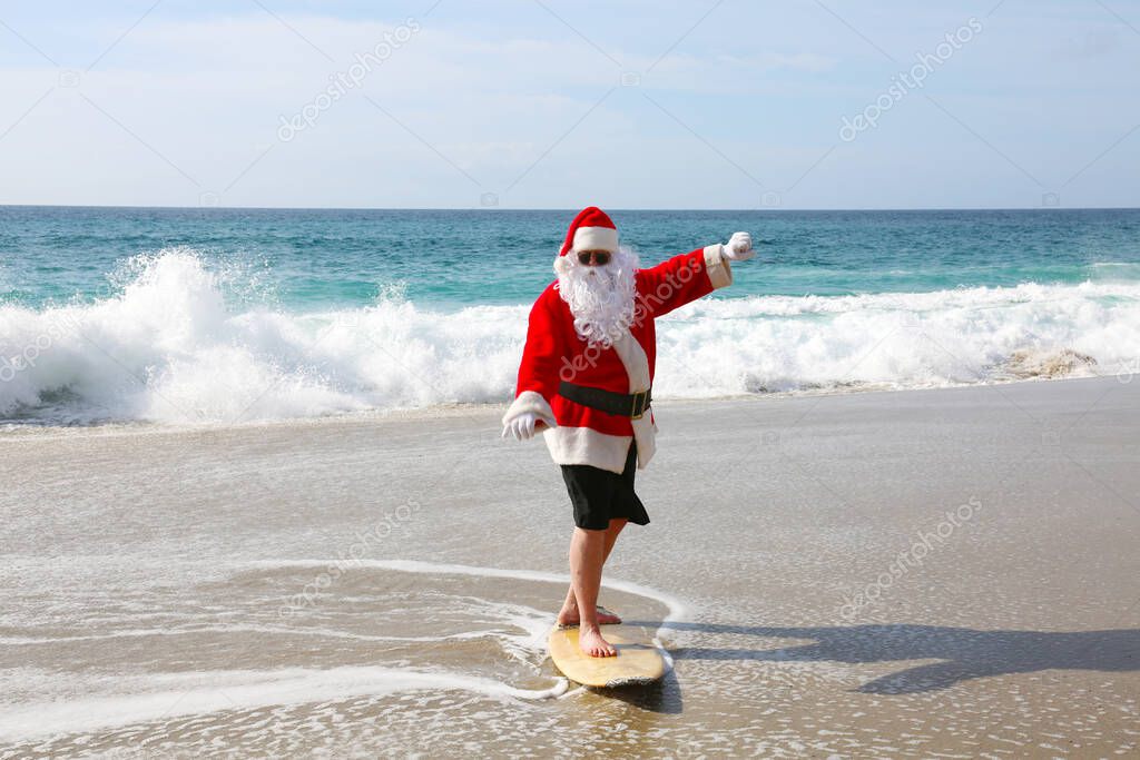 Surfing Santa Claus. Christmas. Christmas Vacation. Surfing Santa. Surf Board. Hang Ten. Santa Claus Rides the waves while on Vacation. Santa Surfs before Christmas Eve. Santa Claus and surf board. Santa Claus Surfs on his Surf Board. Surfs up.