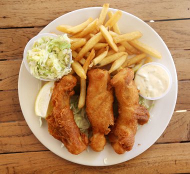 Balık ve patates kızartması. Mahi Mahi balığı ve patates kızartması ve ahşap bir masada beyaz tabakta ananas salatası. Hawaii Balık ve Cips. 