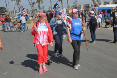 Huntington Sahili, CA - 25 Mart 2017: Amerika 'yı Tekrar Harika Yap Yürüyüşü. Cumhuriyetçi başkan Donald Trump 'ın destekçileri ve protestocuları, Huntington Beach' teki bir MAGA yürüyüşünde bayraklar sallayıp, pankart sallıyorlar. Gururlu Amerikalılar Trump 'ı destekliyor. Başkan Trump.