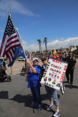 Huntington Sahili, CA - 25 Mart 2017: Amerika 'yı Tekrar Harika Yap Yürüyüşü. Cumhuriyetçi başkan Donald Trump 'ın destekçileri ve protestocuları, Huntington Beach' teki bir MAGA yürüyüşünde bayraklar sallayıp, pankart sallıyorlar. Gururlu Amerikalılar Trump 'ı destekliyor. Başkan Trump.