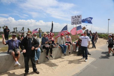 Huntington Sahili, CA - 25 Mart 2017: Amerika 'yı Tekrar Harika Yap Yürüyüşü. Cumhuriyetçi başkan Donald Trump 'ın destekçileri ve protestocuları, Huntington Beach' teki bir MAGA yürüyüşünde bayraklar sallayıp, pankart sallıyorlar. Gururlu Amerikalılar Trump 'ı destekliyor. Başkan Trump.