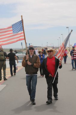 Huntington Sahili, CA - 25 Mart 2017: Amerika 'yı Tekrar Harika Yap Yürüyüşü. Cumhuriyetçi başkan Donald Trump 'ın destekçileri ve protestocuları, Huntington Beach' teki bir MAGA yürüyüşünde bayraklar sallayıp, pankart sallıyorlar. Gururlu Amerikalılar Trump 'ı destekliyor. Başkan Trump.