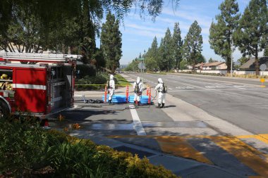 Lake Forest, California, Mayıs 2017: Tehlikeli madde ekibi, yüzme havuzu kimyasalları içeren tek bir kamyon kazasını temizliyor ve zehirli sıvıların çevreye salınmasını engelliyor. Tehlikeli madde kıyafetleri içinde itfaiye ve acil durum ekipleri. 