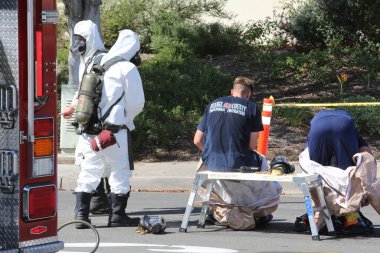 Lake Forest, California, Mayıs 2017: Tehlikeli madde ekibi, yüzme havuzu kimyasalları içeren tek bir kamyon kazasını temizliyor ve zehirli sıvıların çevreye salınmasını engelliyor. Tehlikeli madde kıyafetleri içinde itfaiye ve acil durum ekipleri.