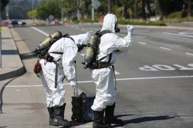 Lake Forest, California, Mayıs 2017: Tehlikeli madde ekibi, yüzme havuzu kimyasalları içeren tek bir kamyon kazasını temizliyor ve zehirli sıvıların çevreye salınmasını engelliyor. Tehlikeli madde kıyafetleri içinde itfaiye ve acil durum ekipleri.