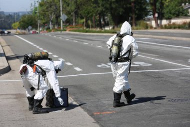 Lake Forest, California, Mayıs 2017: Tehlikeli madde ekibi, yüzme havuzu kimyasalları içeren tek bir kamyon kazasını temizliyor ve zehirli sıvıların çevreye salınmasını engelliyor. Tehlikeli madde kıyafetleri içinde itfaiye ve acil durum ekipleri.
