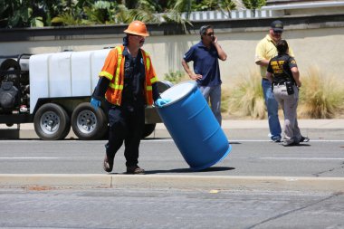 Tehlikeli madde. Lake Forest, California, 23 Mayıs 2017: Tehlikeli madde ekibi, yüzme havuzu kimyasalları içeren tek bir kamyon kazasını temizler ve zehirli sıvıların çevreye salınmasını önler. Tehlikeli madde kıyafetleri içinde itfaiye ve acil durum ekipleri. 