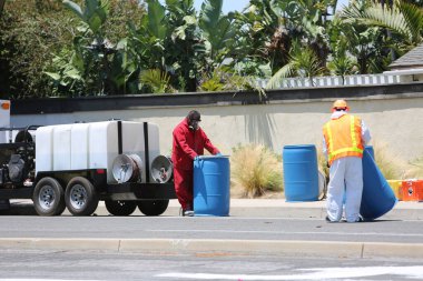 Tehlikeli madde. Lake Forest, California, 23 Mayıs 2017: Tehlikeli madde ekibi, yüzme havuzu kimyasalları içeren tek bir kamyon kazasını temizler ve zehirli sıvıların çevreye salınmasını önler. Tehlikeli madde kıyafetleri içinde itfaiye ve acil durum ekipleri. 
