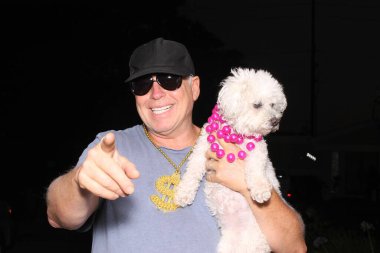 Fotoğraf kabini. Bir adam bir partide köpeğiyle fotoğraf kabininde poz verirken gülümser ve güler. Fotoğraf Booth Party seti. Gözlükler, şapkalar, dudaklar, bıyıklar, fotoğraf kabini partisi için maskeler. Düğün partisi komik resimleri. Köpekler Fotoğraf Kabinlerini sever. 