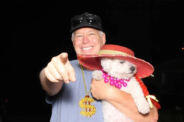 Photo Booth. A man smiles and laughs while posing with his dog for their pictures in a Photo Booth at a party. Photo Booth Party set. Glasses, hats, lips, mustaches, masks for photo booth party. Wedding Party funny pictures. Dogs Love Photo Booths.