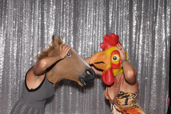 Photo Booth. Two Women wear Animal Head Masks while in a Photo Booth. Horse Head. Chicken Head. Photo Booth party. Wedding Photo Booth. Halloween Photo Booth. Funny Photo Booth. Photo Booth party. Birthday Photo Booth. Retirement Photo Booth. Laugh.
