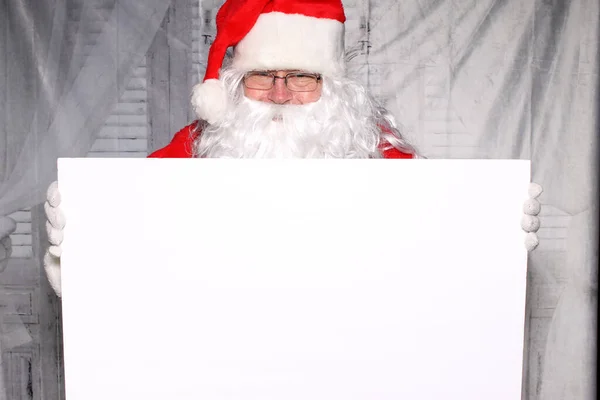 クリスマスだ サンタクロース フォトブース 写真ブースにいるサンタのポーズ サンタクロースは面白いです 楽しいサンタの写真 サンタクロースは白いサインを持っています テキストのための部屋 あなたの画像のための部屋 広告のための部屋 — ストック写真