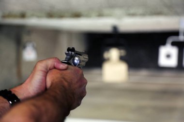 Atış poligonunda eli silahlı bir adam var.