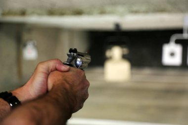 Atış poligonunda eli silahlı bir adam var.