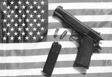1911 hand gun, clip and extra bullets on an American flag. 2nd amendment rights concept.