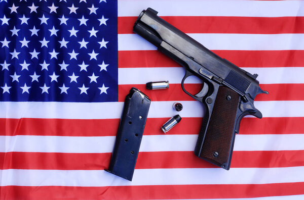 1911 hand gun, clip and extra bullets on an American flag. 2nd amendment rights concept.