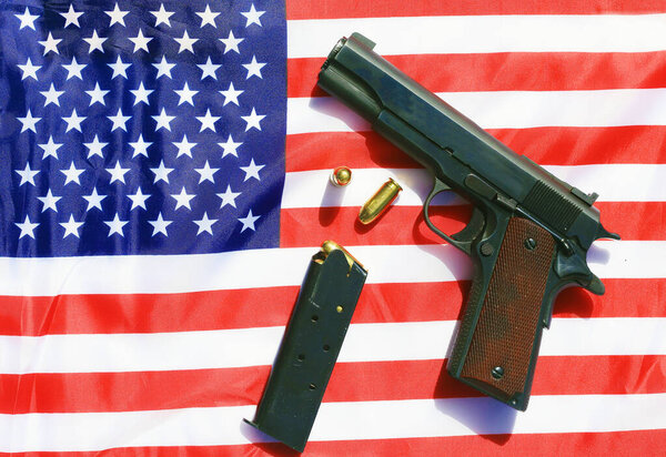 1911 hand gun, clip and extra bullets on an American flag. 2nd amendment rights concept.
