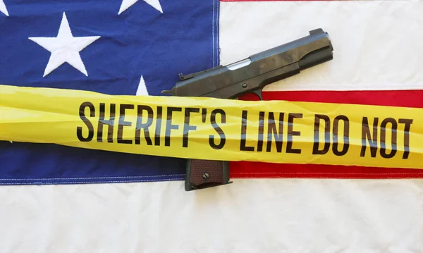 45 pistol with an American Flag, and Sheriff\'s Line Do Not Cross and Crime Scene Tape. Represents the Second Amendment, the right to own guns, and the current anti gun politics. march for life