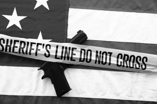45 pistol with an American Flag, and Sheriff\'s Line Do Not Cross and Crime Scene Tape. Represents the Second Amendment, the right to own guns, and the current anti gun politics. march for life