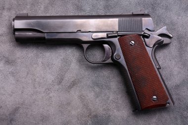 45 caliber 1911 semi automatic pistol. Vintage 1911 .45 caliber pistol on blue grey leather background.