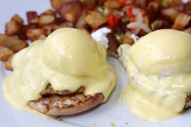 Eggs Benedict and Diced fried potato. Breakfast or Brunch Special with Cheese Sauce. Restaurant Food.
