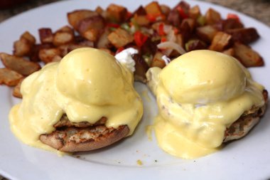 Eggs Benedict and Diced fried potato. Breakfast or Brunch Special with Cheese Sauce. Restaurant Food.