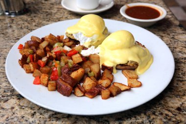Eggs Benedict and Diced fried potato. Breakfast or Brunch Special with Cheese Sauce. Restaurant Food.