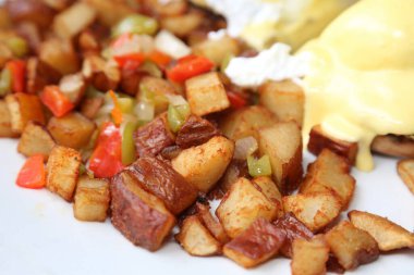 Eggs Benedict and Diced fried potato. Breakfast or Brunch Special with Cheese Sauce. Restaurant Food.
