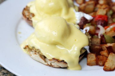 Eggs Benedict and Diced fried potato. Breakfast or Brunch Special with Cheese Sauce. Restaurant Food.