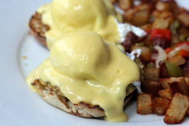 Eggs Benedict and Diced fried potato. Breakfast or Brunch Special with Cheese Sauce. Restaurant Food.
