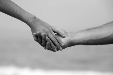 Engagement Couple holding hands with a beach background. A couple hold hands with a wedding ring and Laguna Beach California Background.