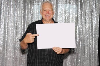 man with blank sign. A Man in a Photo Booth with a Blank Sign. Room for text. Silver sequin background photo booth.