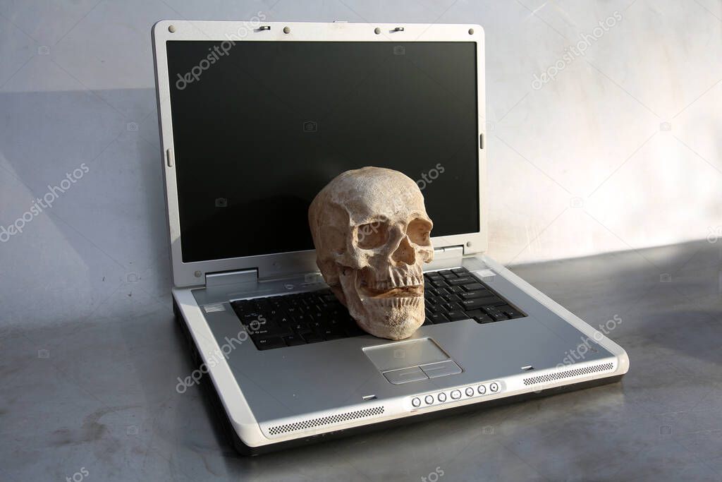 Halloween. Human Skull on Laptop Computer. Haunted Computer. Haunted Laptop. Halloween Human Skull. Evil Skeleton. Covid-19 Halloween Human Skull. A Spooky Monstrous Human Skull Isolated on Black. Coronavirus Human Skull in black. Covid-19. Covid-19.