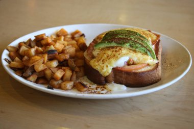 Eggs Benedict. Egg Benedict Breakfast with Diced Potato's Cheese Sauce and Avocado slices.