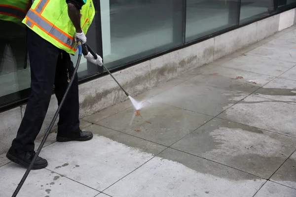 Pressure Washing. An unidentifiable city employee power washes blood or ketchup off a city sidewalk in downtown Los Angeles California.
