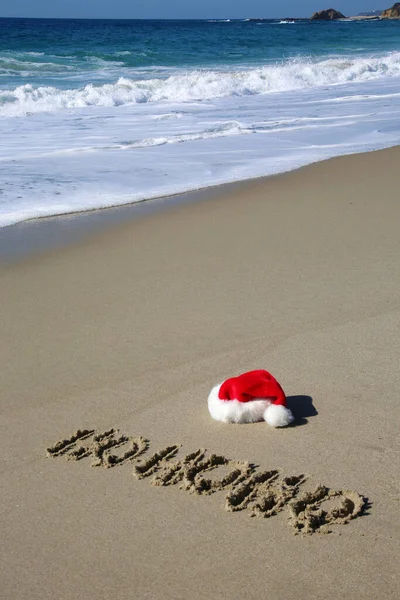 Santa Hat. Santa Claus hat on the beach with the word HO HO HO written in the sand. Room for text. Words can be removed and replaced with your own.