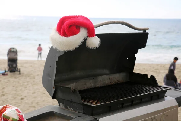 烧烤烤架上的圣诞老人帽子 在海滩上与圣诞老人帽的烧烤烧烤架 — 图库照片