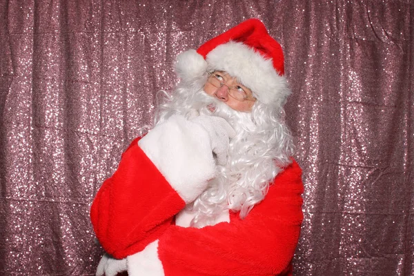 Santa Claus. Santa Claus is Deep in thought. Santa Thinks about things while in a Photo Booth with pink sequin curtains.