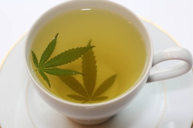 Yeşil marihuana yapraklı çay fincanında kenevir çayı. Uyku ve endişe için tıbbi amaçlar. Marihuana çayı ve sağlıklı içecek konsepti. Esrar yapraklı kenevir çayı. Tıbbi marihuana çayı. Marihuana Yapraklı Esrar Çayı. 