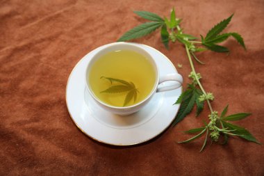 Yeşil marihuana yapraklı çay fincanında kenevir çayı. Uyku ve endişe için tıbbi amaçlar. Marihuana çayı ve sağlıklı içecek konsepti. Esrar yapraklı kenevir çayı. Tıbbi marihuana çayı. Marihuana Yapraklı Esrar Çayı. 