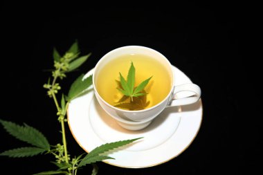 Yeşil marihuana yapraklı çay fincanında kenevir çayı. Uyku ve endişe için tıbbi amaçlar. Marihuana çayı ve sağlıklı içecek konsepti. Esrar yapraklı kenevir çayı. Tıbbi marihuana çayı. Marihuana Yapraklı Esrar Çayı. 