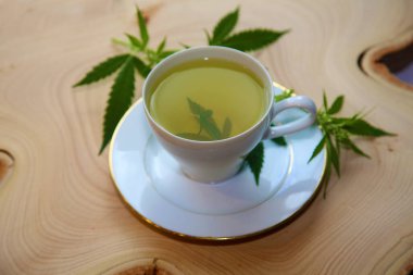 Yeşil marihuana yapraklı çay fincanında kenevir çayı. Uyku ve endişe için tıbbi amaçlar. Marihuana çayı ve sağlıklı içecek konsepti. Esrar yapraklı kenevir çayı. Tıbbi marihuana çayı. Marihuana Yapraklı Esrar Çayı. 