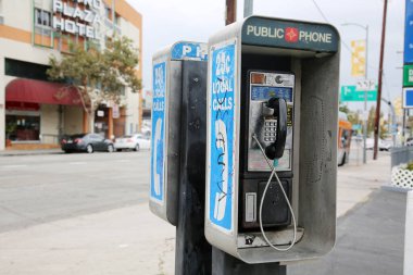 Los Angeles, California - ABD - 27 Ağustos 2021: Güneşli bir günde şehir kaldırımında eski, kirli bir paralı telefon gösteriliyor. Kullanım için genel ödemeli telefon. 