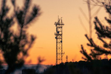 Telekomünikasyon kulesi turuncu bir günbatımının arka planında 