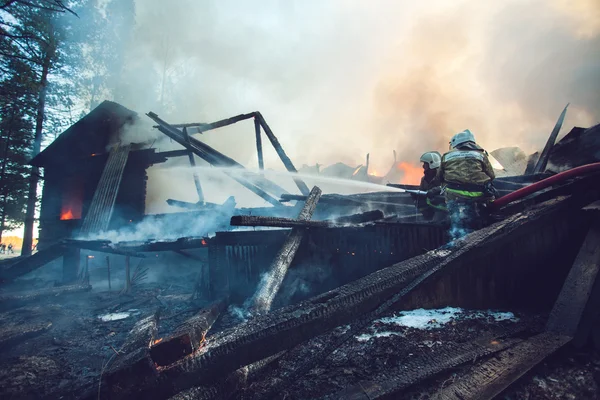Strezhevoy, RUSSIA - 21 Mei 2014: Pemadam kebakaran memadamkan api di sebuah rumah kayu — Stok Foto