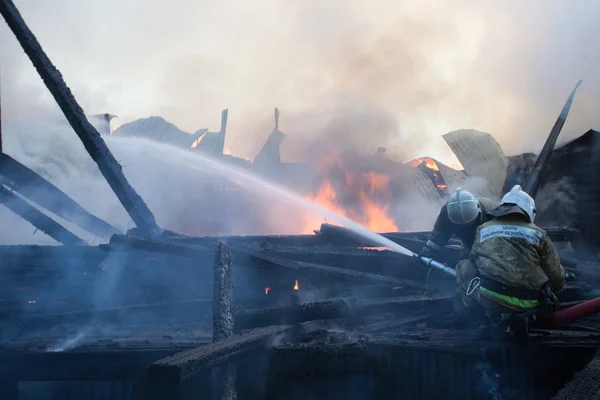 Strezhevoy, RUSSIA - 21 maggio 2014: L'uomo spegne il fuoco con acqua Immagine Stock