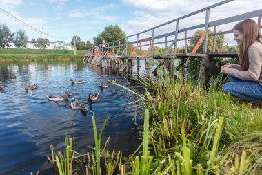 Ördekler Suzdal içinde ahşap bir köprüde besleme kız