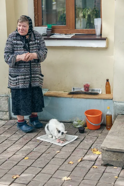 Suzdal, RÚSSIA - set 13, 2015: Boa avó alimentando um gato vadio — Fotografia de Stock
