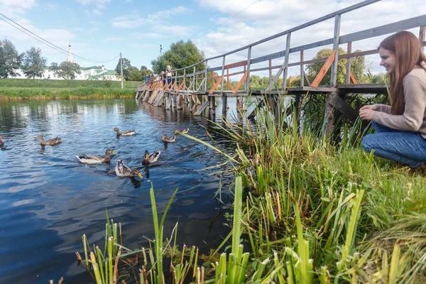 Ördekler Suzdal içinde ahşap bir köprüde besleme kız